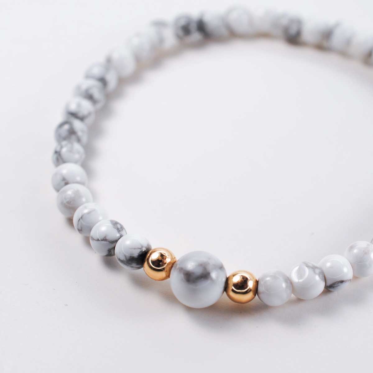 White howlite gemstone horizon bracelet with gold filled bead accents, 6.5-inch elastic design for calm and clarity.
