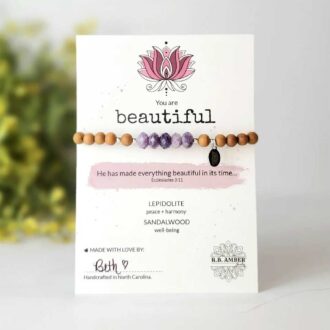 Lepidolite and sandalwood gemstone bracelet with faceted purple beads, displayed on inspirational “You Are Beautiful” card.