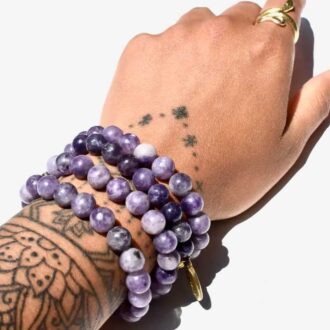 Lepidolite beaded bracelet with deep purple tones, worn stacked for calming energy and stress relief.