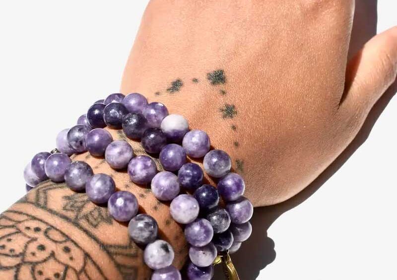 Lepidolite beaded bracelet with deep purple tones, worn stacked for calming energy and stress relief.