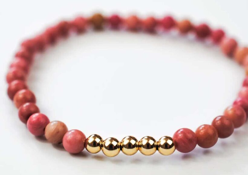 Rhodonite Ascension bracelet with pink gemstone beads and five gold-filled accent beads on a white background.