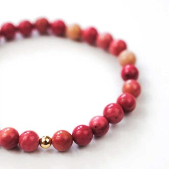 Rhodonite Solo Core bracelet with pink gemstone beads and a single gold-filled accent bead on a white background.