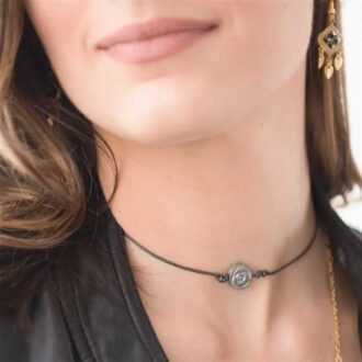 Rose hematite choker necklace with matte hematite rose bead on black leather cord worn at the neck.