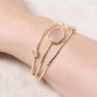 Gold hammered bracelet with rose quartz gemstones, worn on wrist.