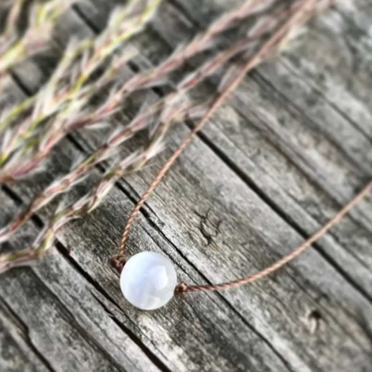 Minimalist selenite round gemstone necklace on light brown cord with sterling silver clasp, 18-inch length, designed for serenity and balance.