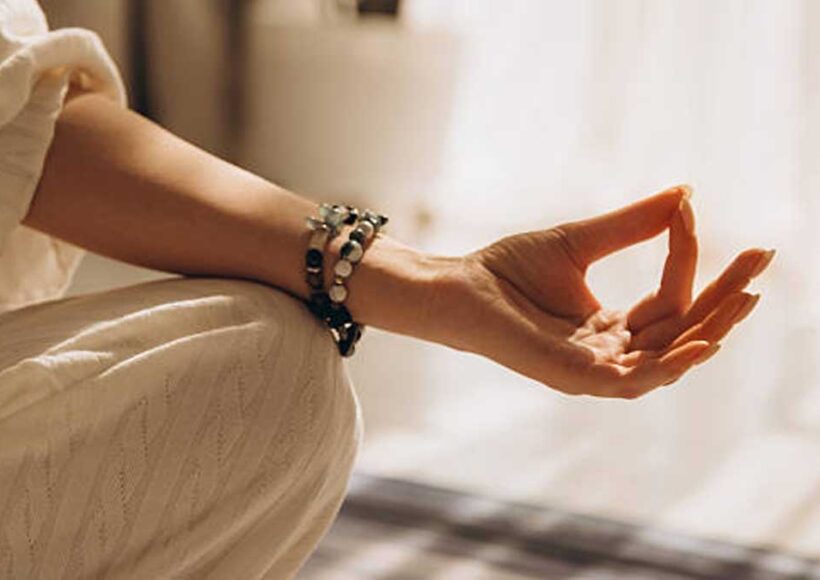 Woman meditating wearing gemstone meditation jewelry bracelet on wrist