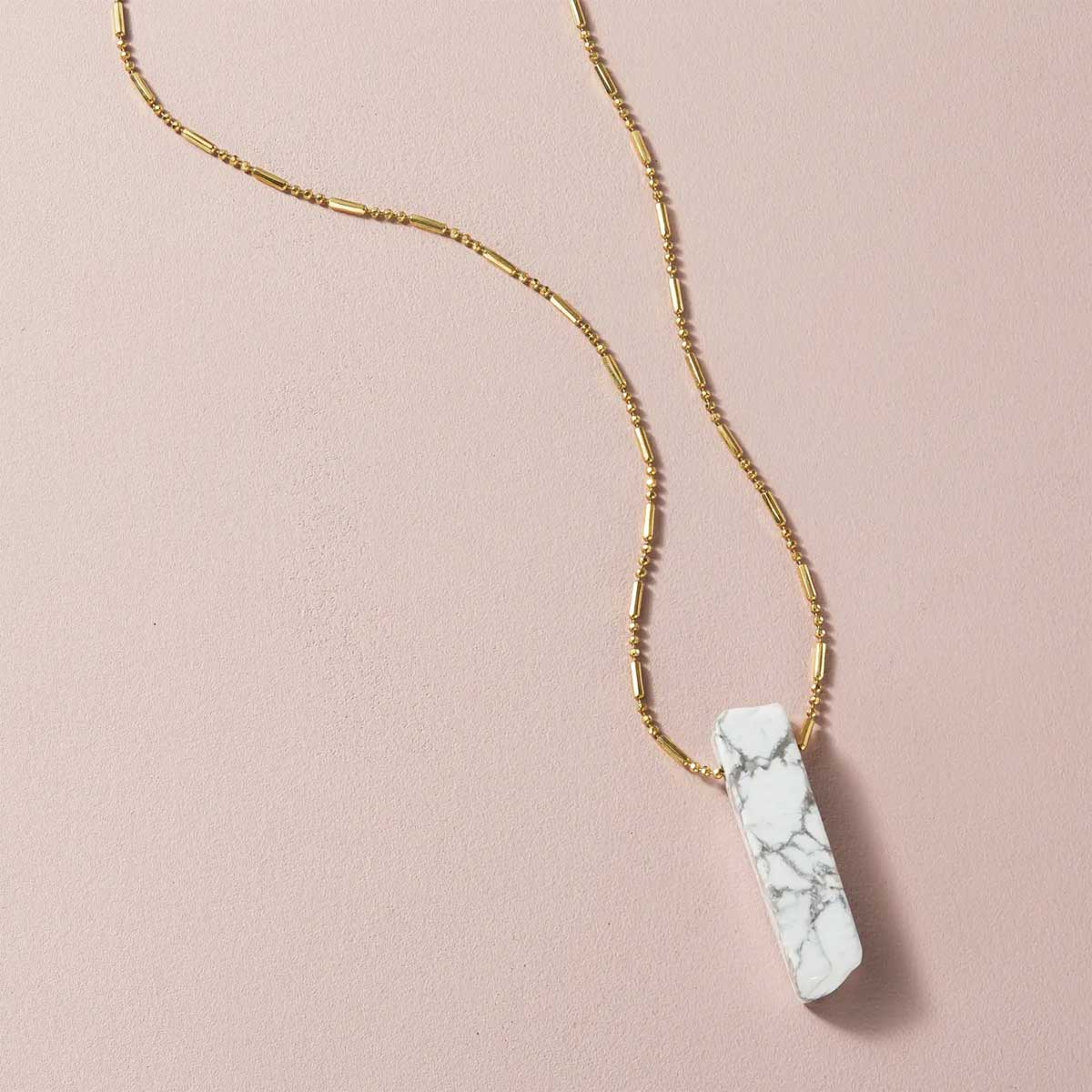 White howlite crystal point necklace on a gold beaded chain, designed for calm, clarity, and spiritual balance.