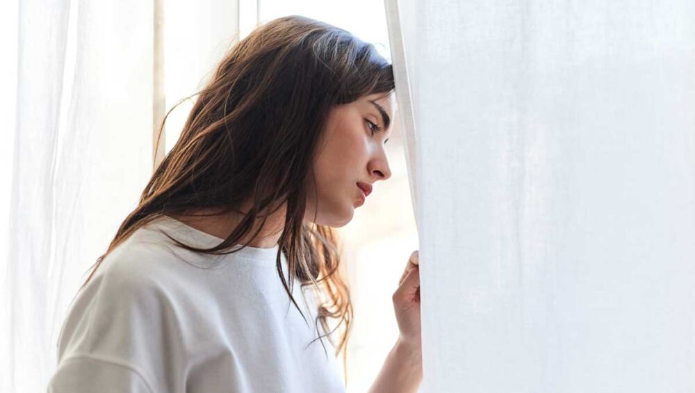 woman looking thoughtfully out the window, symbolizing emotional reflection and sensitivity