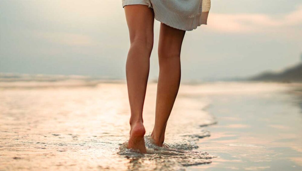 barefoot person walking along the beach at sunset to practice grounding and mindfulness
