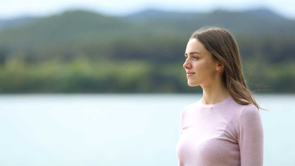 woman standing calmly by the water, symbolizing peace and healthy emotional boundaries