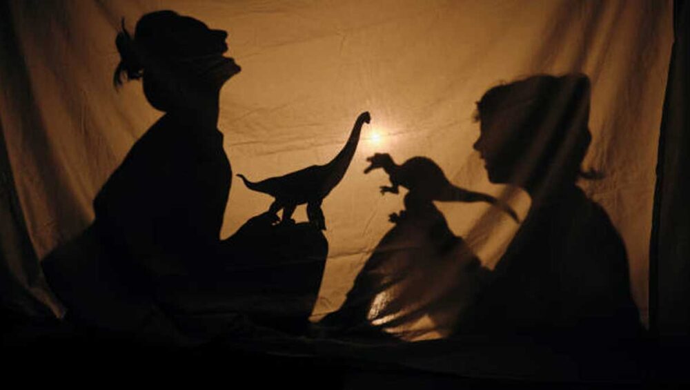 silhouettes playing with dinosaur toys behind a backlit sheet, symbolizing inner child healing