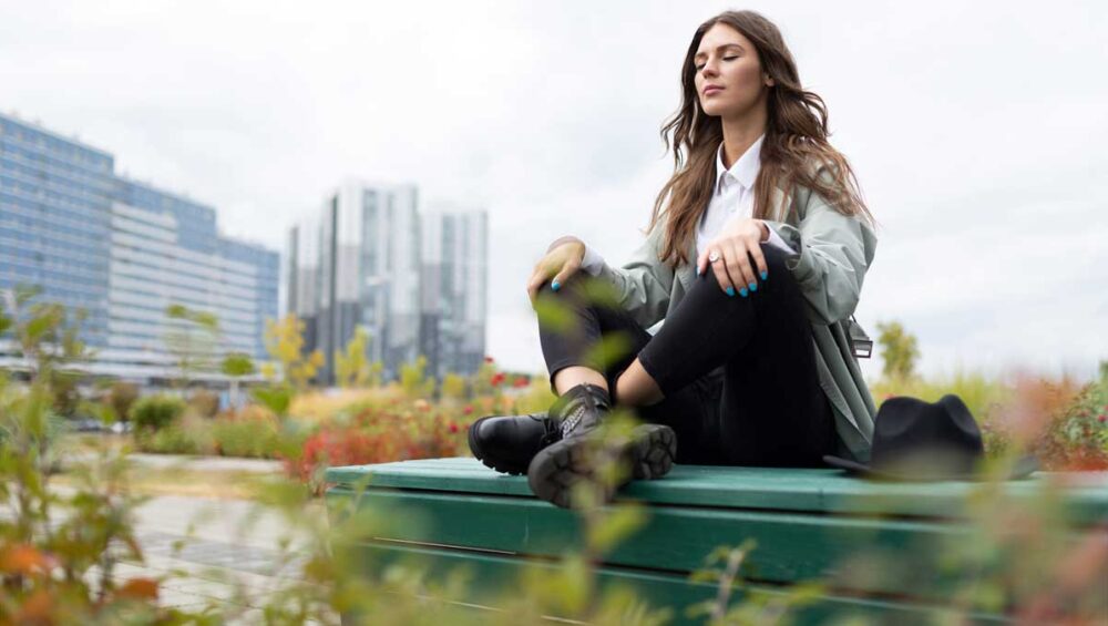 woman practicing mindfulness and grounding in a city park surrounded by greenery