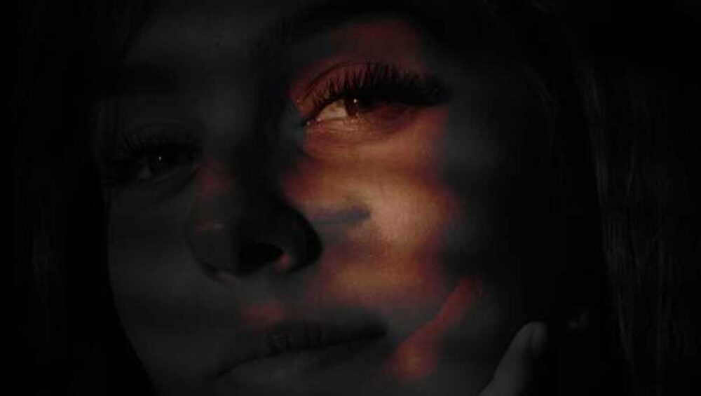 woman’s face in shadow with warm light highlighting one eye, symbolizing the hidden highs and lows of narcissistic euphoria