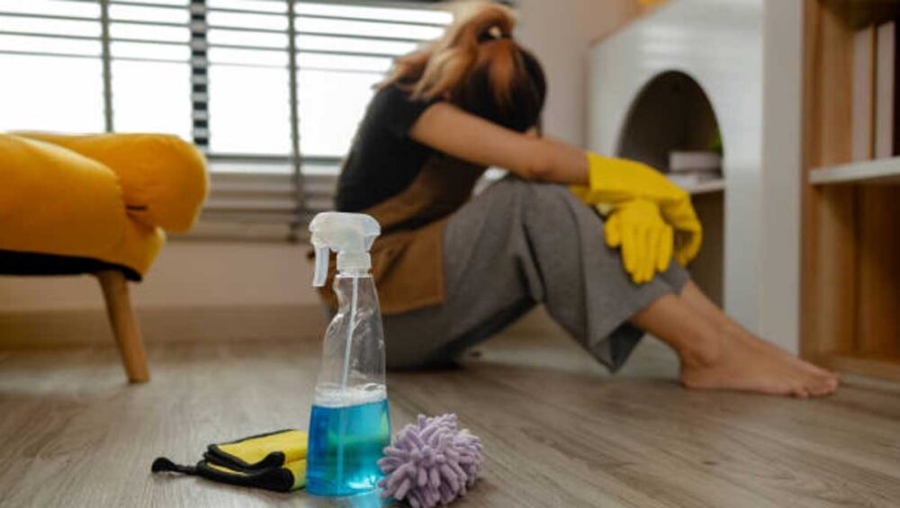 A person sitting on the floor in cleaning gloves, emotionally exhausted after constant acts of service driven by trauma.