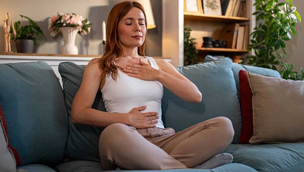 woman practicing breathwork with one hand on chest and one on belly