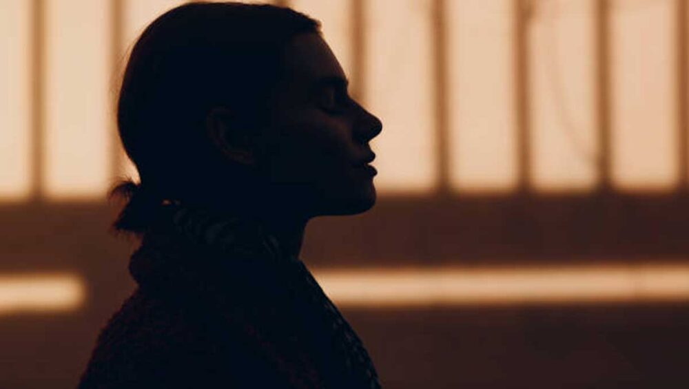 Silhouette of a woman in soft warm light with her eyes closed, symbolizing inner peace and intuitive awareness.