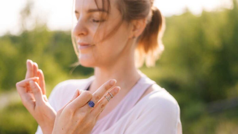 woman meditating outdoors wearing a lapis lazuli ring for emotional clarity and truth
