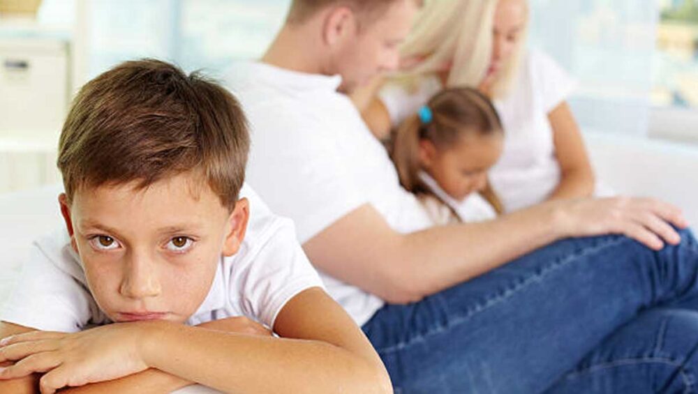 Child feeling emotionally isolated while family interacts in the background
