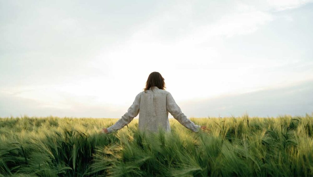 person standing in a field at sunrise symbolizing healing and rebuilding self-worth