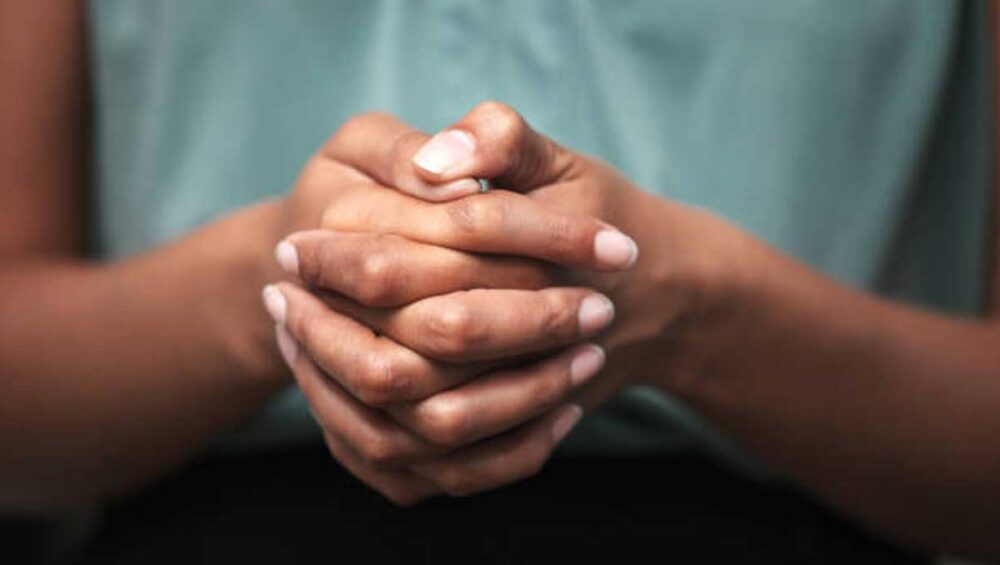 hands gently clasped in a self-soothing gesture symbolizing reparenting for scapegoat survivors