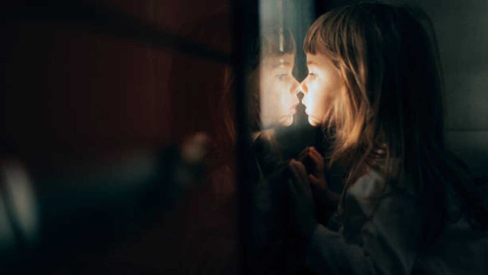 child looking at her reflection in soft light symbolizing inner child healing and narcissistic mother trauma