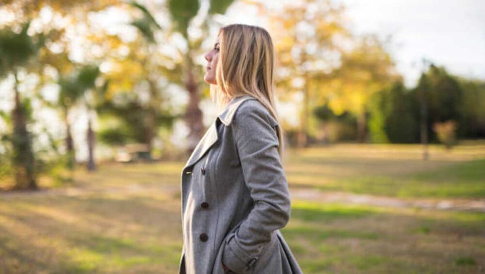 woman standing quietly outdoors with hands in pockets, symbolizing the calm strength of a stoic empath