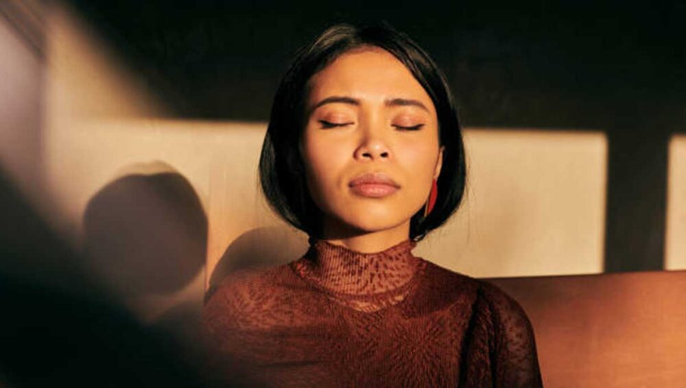 woman sitting peacefully with eyes closed in warm sunlight, representing intuitive empathy