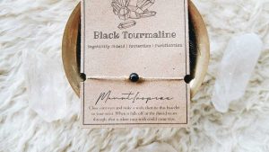 Black tourmaline bracelet displayed on a neutral card with soft natural textures