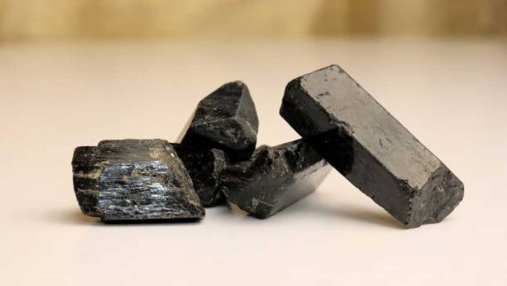 raw black tourmaline stones resting on a neutral surface