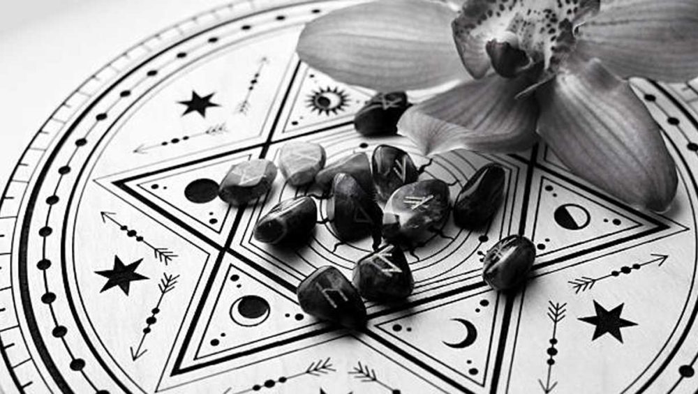 Black and white altar cloth with a pentagram design, small stones, and an orchid flower