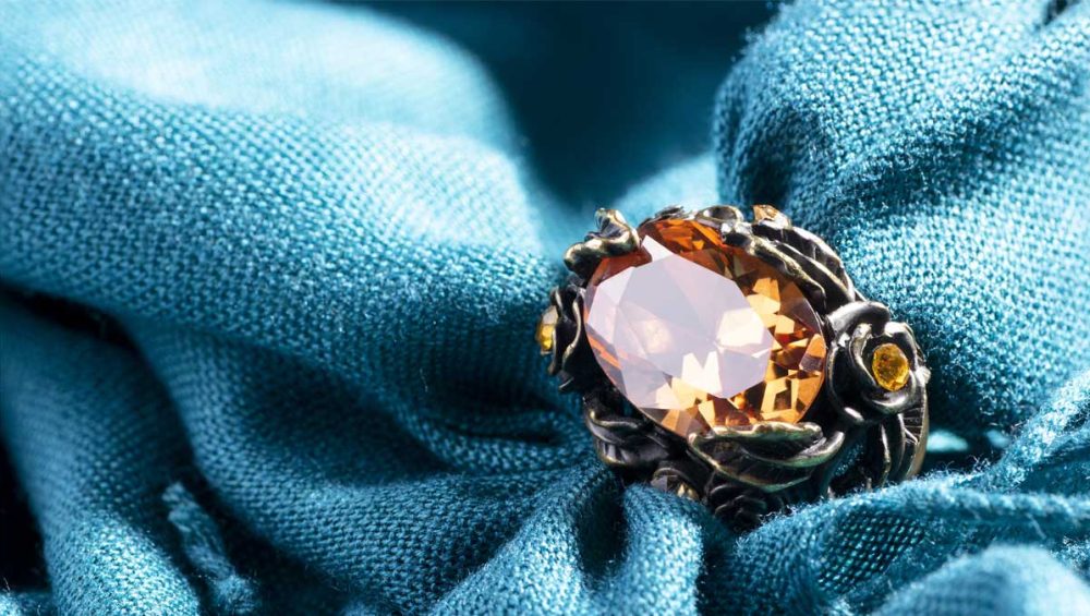 citrine gemstone ring resting on soft blue fabric