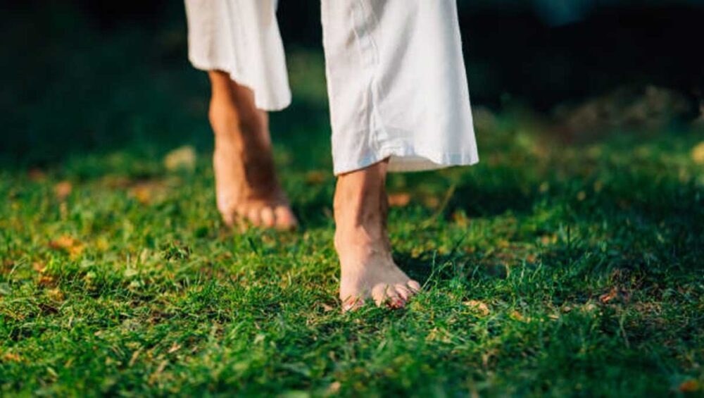 Bare feet walking on green grass outdoors in soft sunlight