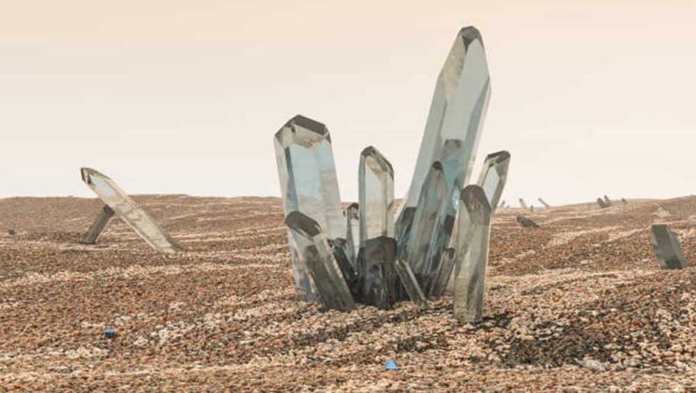 Cluster of clear crystal points rising from a sandy, rocky landscape under a pale sky
