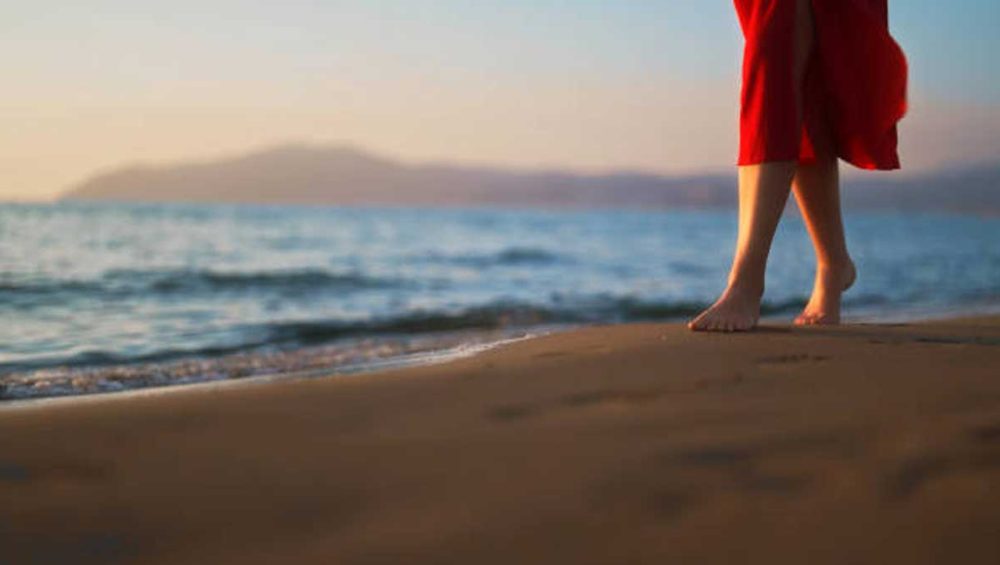 Bare feet walking along the shoreline at sunset