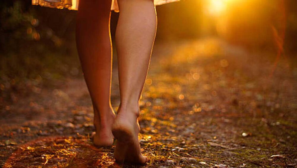 Barefoot person walking on a forest path in warm sunset light