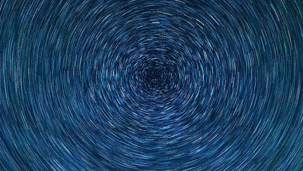 Circular star trails forming a spiral pattern in a dark blue night sky.