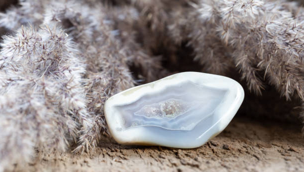 A pale blue lace agate stone resting on soft, natural textures.