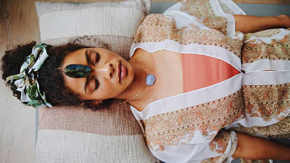 A person resting with a blue lace agate stone placed at the throat area.
