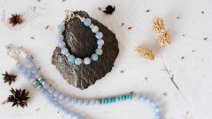 Blue lace agate bracelet and necklace arranged on a stone with dried florals