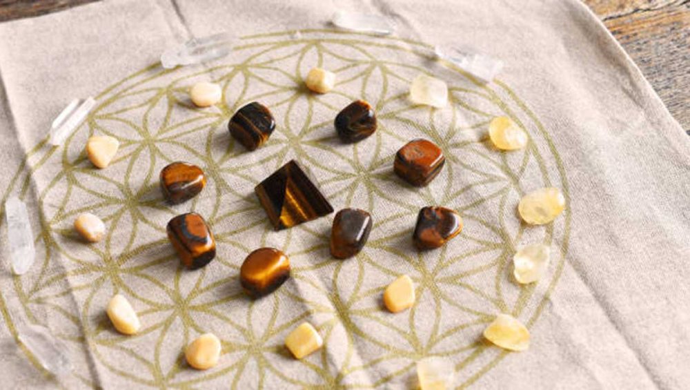 Tiger’s eye and citrine crystals arranged in a flower of life crystal grid on a linen cloth.