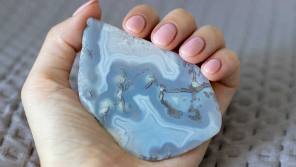 Blue lace agate stone with soft blue banding held in a hand