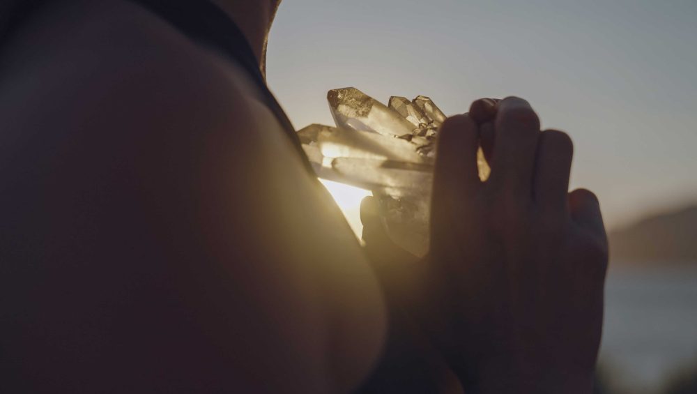 Person holding a glowing crystal in warm sunlight symbolizing citrine for solar plexus chakra energy