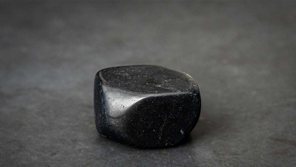 Polished black onyx stone resting on a dark matte surface