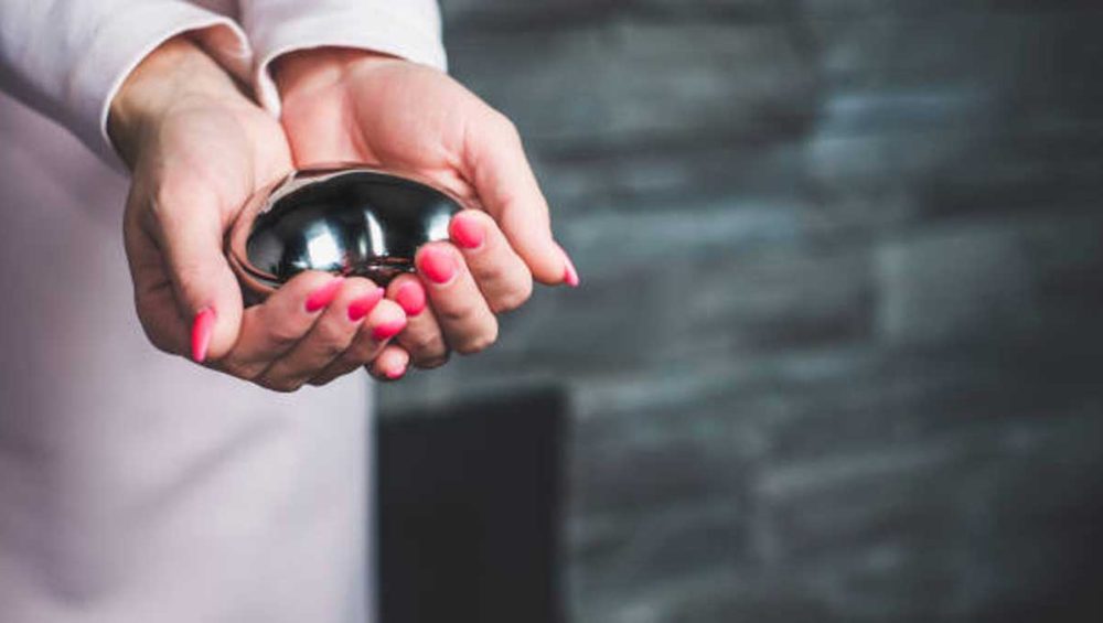 Hands holding a polished dark metallic hematite stone