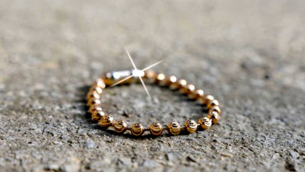 gold beaded bracelet reflecting light on a textured surface, showing a polished tarnish-resistant finish