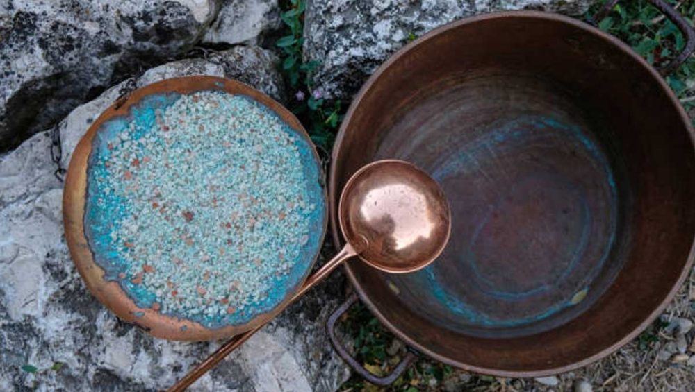 copper bowls with turquoise-colored mineral deposits and textured stones outdoors