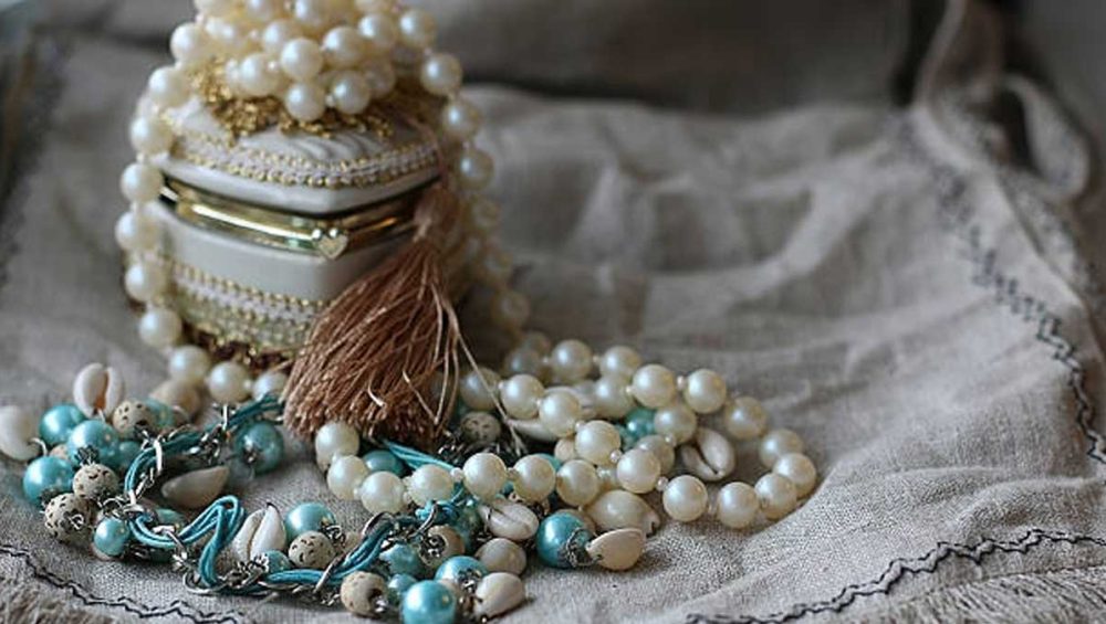 turquoise and pearl jewelry with beaded strands resting on soft fabric beside a decorative box