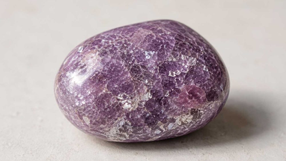 Close-up of a polished lepidolite gemstone showing its natural lavender color and shimmering crystalline texture.