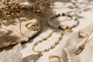 A collection of meaningful jewelry pieces arranged on soft linen with natural light, including gemstone necklaces, bracelets, and rings for emotional wellness.