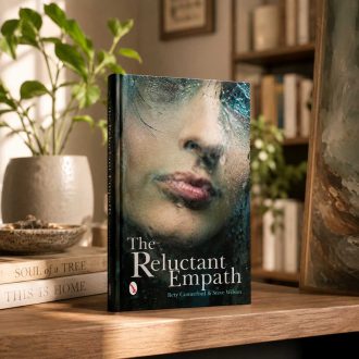 Hardcover copy of The Reluctant Empath displayed on a wooden shelf with soft natural light and greenery in the background.